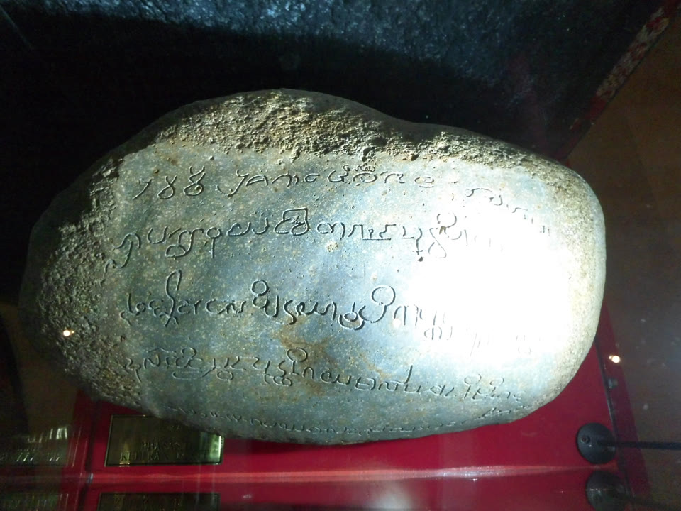 Batu Bersurat Kedukan Bukit, tahun 683, kini disimpan di Muzium Nasional Indonesia, Jakarta. Ini adalah foto pameran — batu ini asalnya didirikan di tebing sungai di pinggir bandar Palembang, dan hanya digali pada tahun 1920, maka gambar ini tidak dapat menggambarkan kedudukan asalnya.