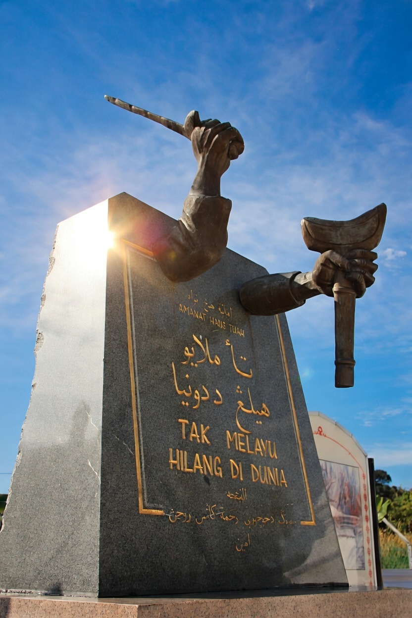 汉都亚誓言碑(Tugu Amanat Hang Tuah)立在马六甲汉都亚陵墓旁,碑上刻着相传出自汉都亚的名句:「Takkan Melayu hilang di dunia」(马来人绝不会消失于世间)。汉都亚是否确有其人,至今仍可讨论;这句话却早已进入马来西亚的政治与文化记忆。此处所写五个少年海边立誓,是文学叙事,并非碑文记载的历史场景。